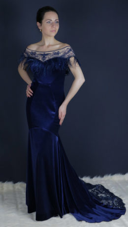 woman wearing long blue velvet party dress with feathers