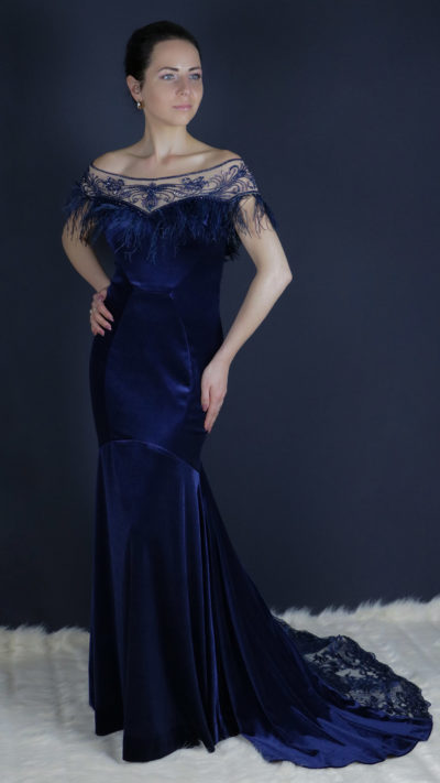 woman wearing long blue velvet party dress with feathers