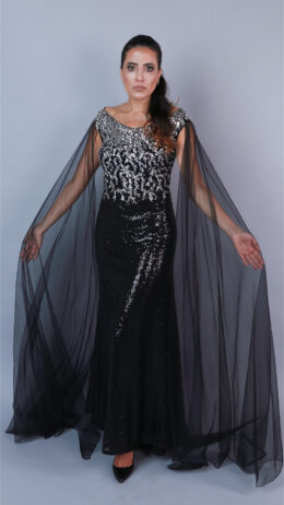 Woman posing in cape effect sequin evening gown black and silver in colour