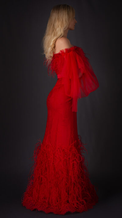 woman wearing long off the shoulder dress red colour embellished with crystals and feathers view from the back